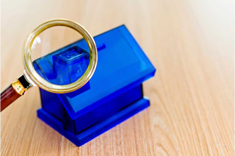 Small blue housing model with magnifying glass