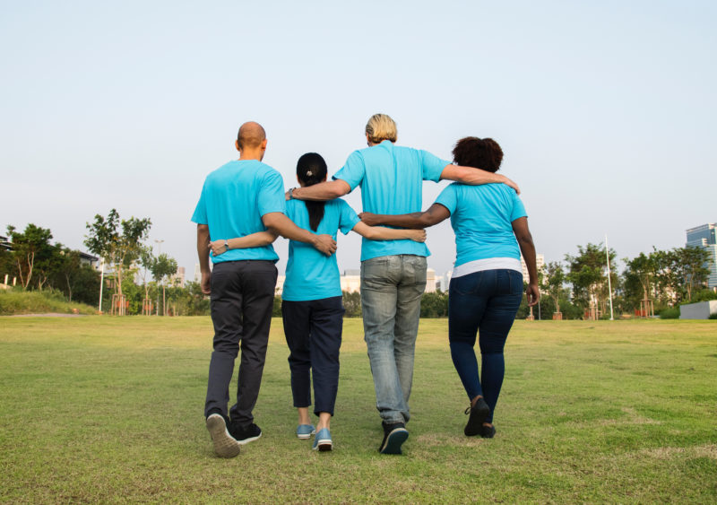 Four people wearing blue tshirts with arms around each other