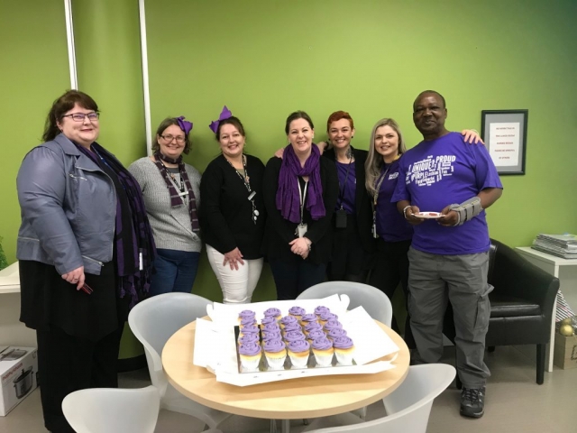 Seven people in front of purple cupcakes